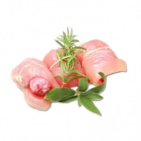 Raw turkey rolls wrapped around sausage with fresh herbs on a white background.